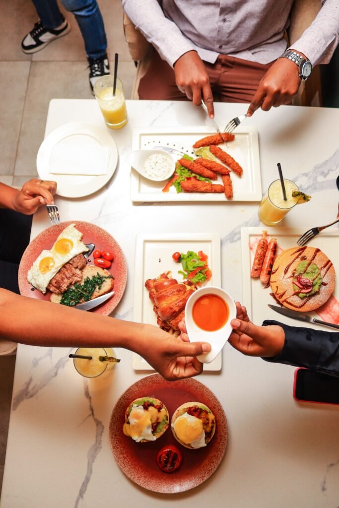 Top view of hands serving and enjoying a variety of brunch dishes at a table, fostering communal dining.